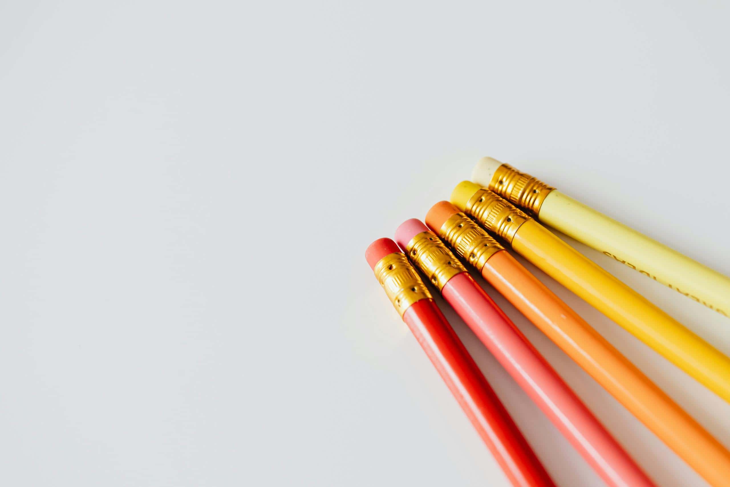 A set of colorful pencils with erasers arranged on a white surface. Perfect for education themes.